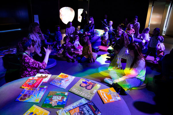 Families enjoying the Hobson's Bay Library Story Time in the Beyond Perception exhibition, during Little Kids Day In - Caring for Country program at Scienceworks, August 2022.