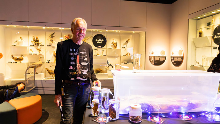 A museum expert stands beside marine collection items in jars during Halloween at the Museum.