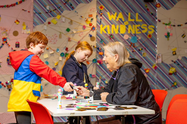 Children being helped to write supportive notes for the wall of kindness.