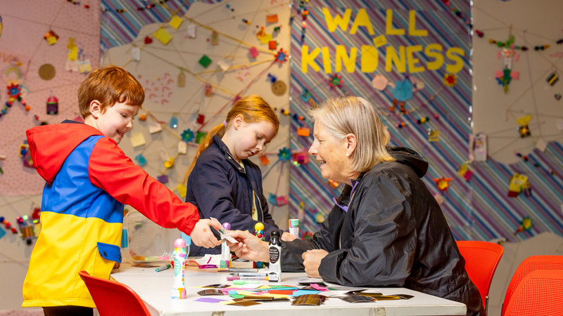 Children being helped to write supportive notes for the wall of kindness.