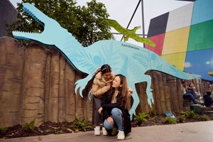 A girl and woman pose in front of the Australovenator in metal cut out in the Gandel Gondwana Garden