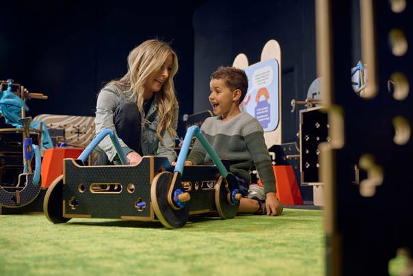 A Blonde woman and brunette boy build a wheeled contraption in Tinkertown