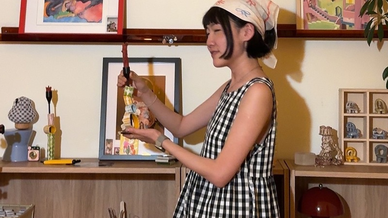 Amy Yang in a checkered dress holding a crafted candle stick holder.