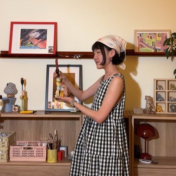 Amy Yang in a checkered dress holding a crafted candle stick holder.