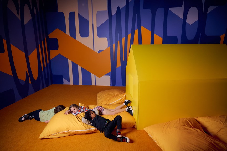 Children recline on large yellow pillows.