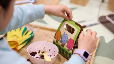 Child packing up a carton of seeds in pots.