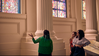 A tour guide shows stained glass windows of the Immigration Museum.