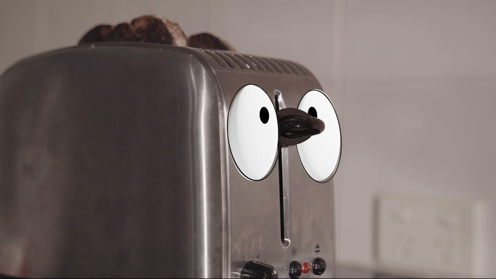 Silver toaster with cartoonish eyes.
