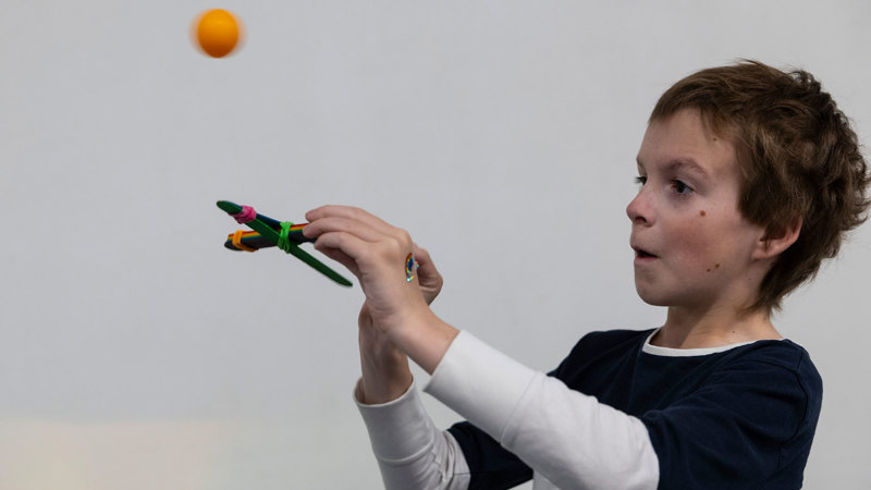 Child used paddlepop sticks, rubber bands and a ping pong ball to make a catapult during a workshop at Scienceworks