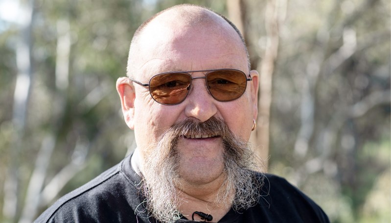 Portrait photo of bald man with large handlebar mustache wearing aviator sunglasses