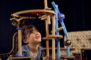 A child developing STEM skills by engineering a structure out of loose parts in Tinkertown exhibition at Scienceworks.