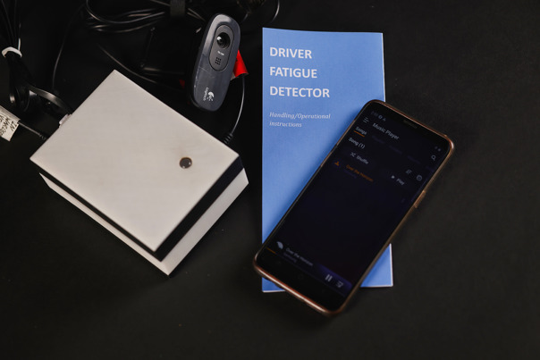 Small black box with a camera next to an instruction manual.