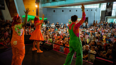 Emma Memma performing on stage in Melbourne Museum foyer.