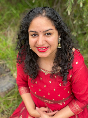 Manjari smiles at the camera. Manjari wears a red traditional dress.