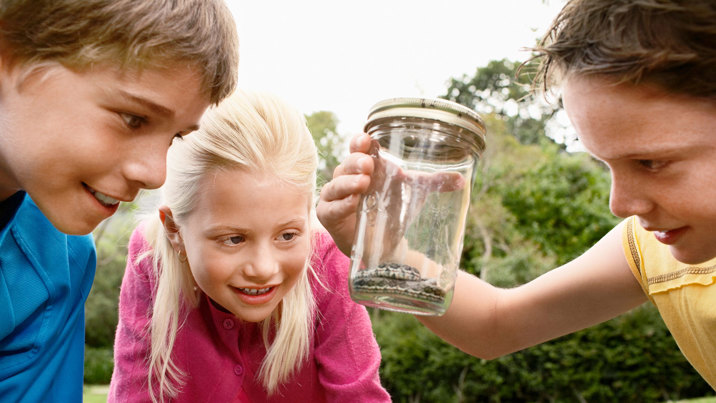 Kids hold a jar with a snake in it