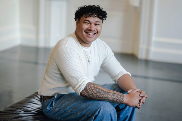 Logan Tapuala sitting and smiling at the camera.