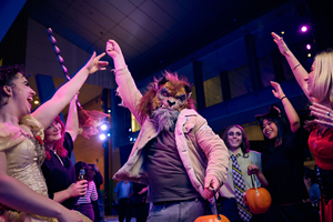 A man dressed as American teen wolf surrounded by people dressed as a vampire, a witch, zombies and cat on the dancefloor.