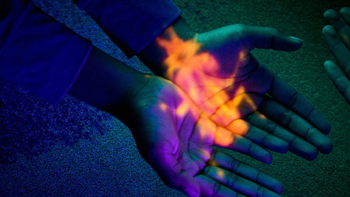 A projection of an orange bug on cupped hands during Halloween at the Museum, Melbourne Museum.
