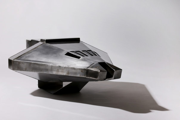 Metal model of an angular space shuttle with faceted silver-toned surfaces and geometric windscreen openings, mounted on a display stand.
