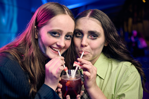 Two people dressed as zombies share a mocktail.