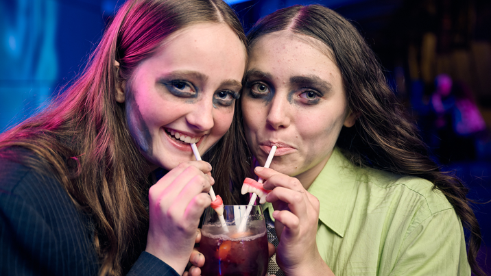 Two people dressed as zombies share a mocktail.