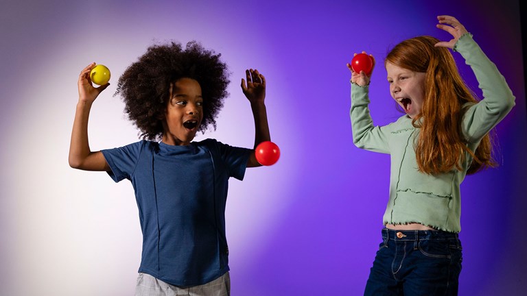 Two children with an excited expressions. They are holding balls