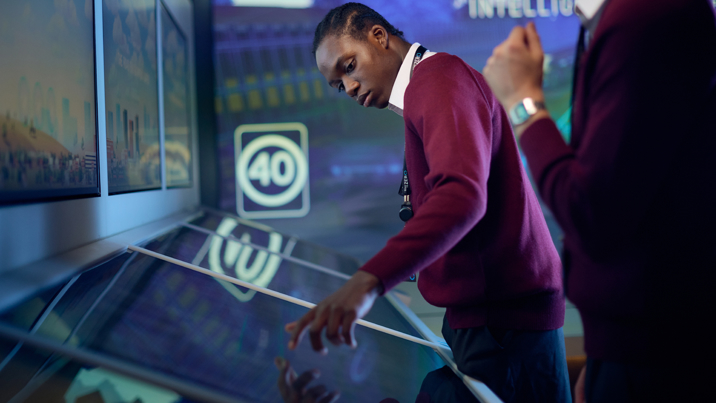 A visitor wearing a school uniform interacts with a touch screen in the Road to Zero Experience Space 