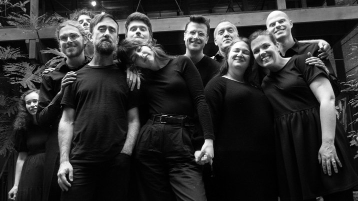 Eleven people wearing all black are pose and smile at the camera.