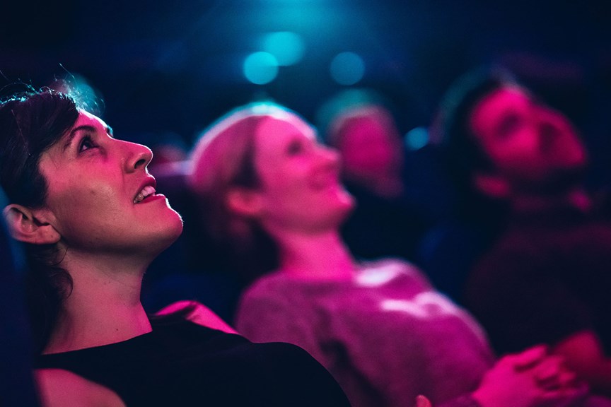 Closeup of faces looking up at the domed planetarium screen.
