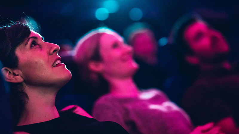 Closeup of faces looking up at the domed planetarium screen.