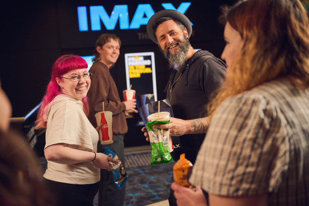 Adults grabbing choctops, popcorn and snacks from the candy bar before seeing a private IMAX screening during Adult Museum Sleepovers at Melbourne Museum.
