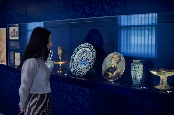 A woman looking at ornate plates on display in the basement of the Royal Exhibition Building.