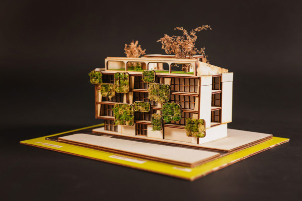 Architectural model of a multi-storey building, featuring vertical garden panels and trees atop the roof. 
