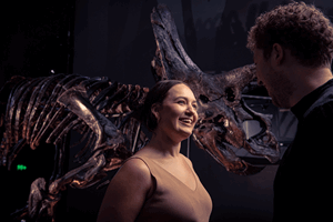 A couple share an animated discussion while standing next to Horridus the Triceratops.