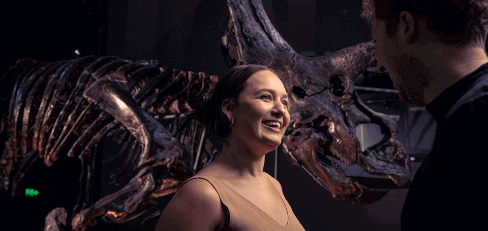 A couple share an animated discussion while standing next to Horridus the Triceratops.