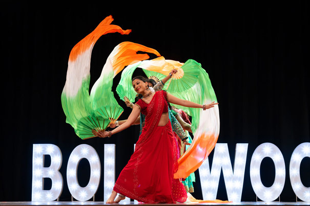 Sapphire Dancers doing a bollywood dance with fans attached to silk scarf-life streamers in grren, white and orange stripe.