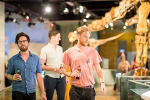 Three friends drinking beers as they walk along Dinosaur Walk exhibition.