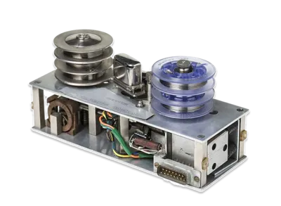 Metal reel-to-reel data storage component with exposed wiring, pulleys and electronic connectors.