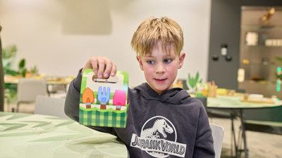 A small child holding their boxed potted seed ready to take home after taking part in the Seed Stories workshop at Melbourne Museum.