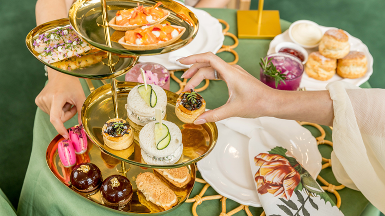 two people share plates of delicious treats on a multi-level gold cake stand.