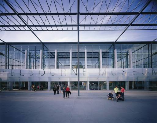 Exterior of Melbourne Museum showing glass facade and entrance, with people on the plaza