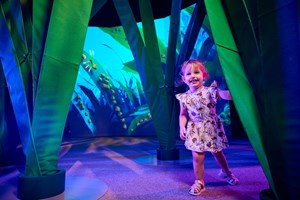 a small child playing among the giant grass blades on antopia exhibition.