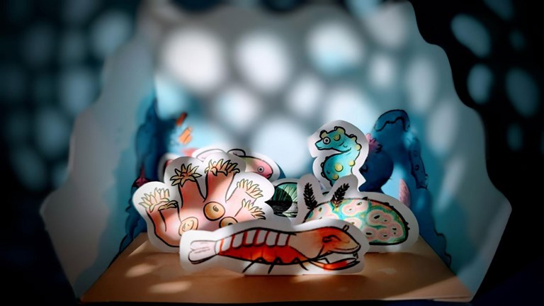 A front view of a paper coral reef diorama showcasing various underwater animals.