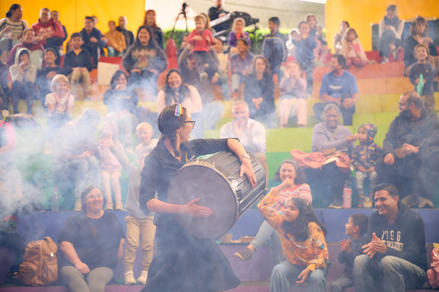 A person hitting an air cannon filled with fog towards an audience. There is a lot of fog visible in the image.