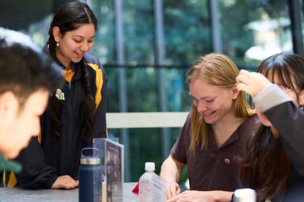 A student facilitator runs an activity with three other students who are folding origami together. 