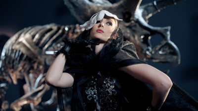 A women wearing a lacey and feathered black fancy outfit and a white rabbit mask.