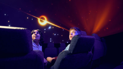 A secondary school student views a representation of a black hole on the dome of the Melbourne Planetarium.