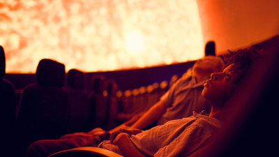 Primary and secondary school students attending an excursion and viewing a projection of the sun on the dome of the Melbourne Planetarium.