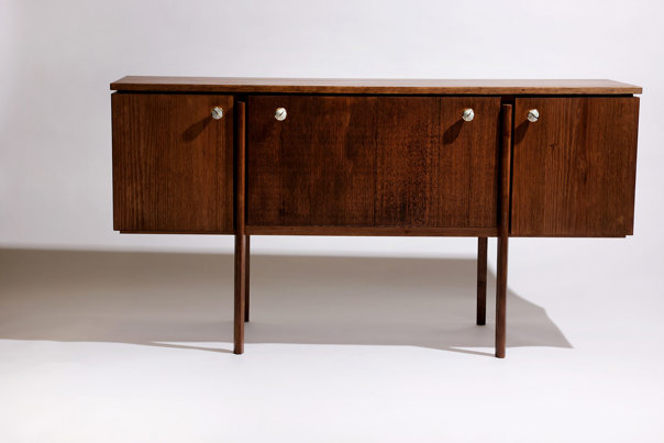 Low, rectangular sideboard in dark-stained timber with four polished-brass disc handles, three storage compartments with sliding doors, and slender squared legs.