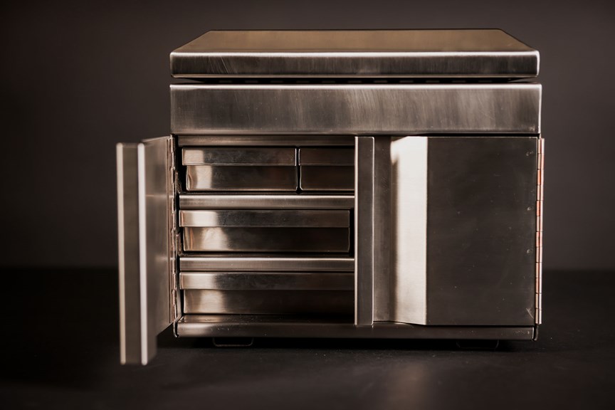 A stainless steel jewellery box with one of its doors open, revealing a series of small shelves inside.